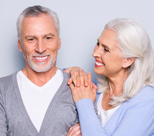 Smiling senior couple with healthy teeth, representing confidence after replacing missing teeth with dental implants