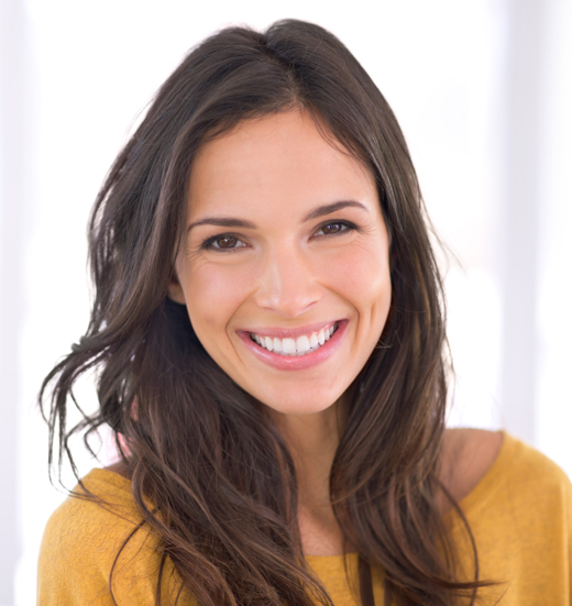 Professional headshot of smiling woman with long dark hair wearing mustard yellow top