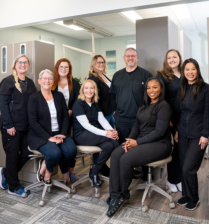 Professional team of nine people in business attire posing together in modern office setting.