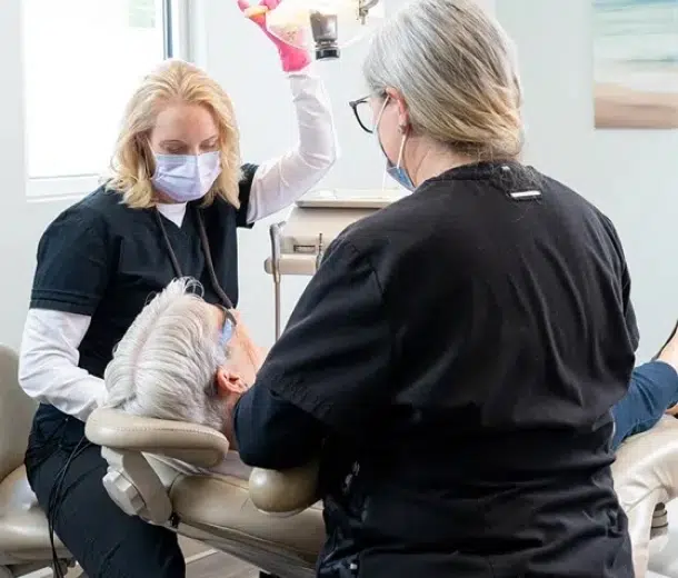 Two healthcare professionals examining a patient's leg in a medical clinic setting.
